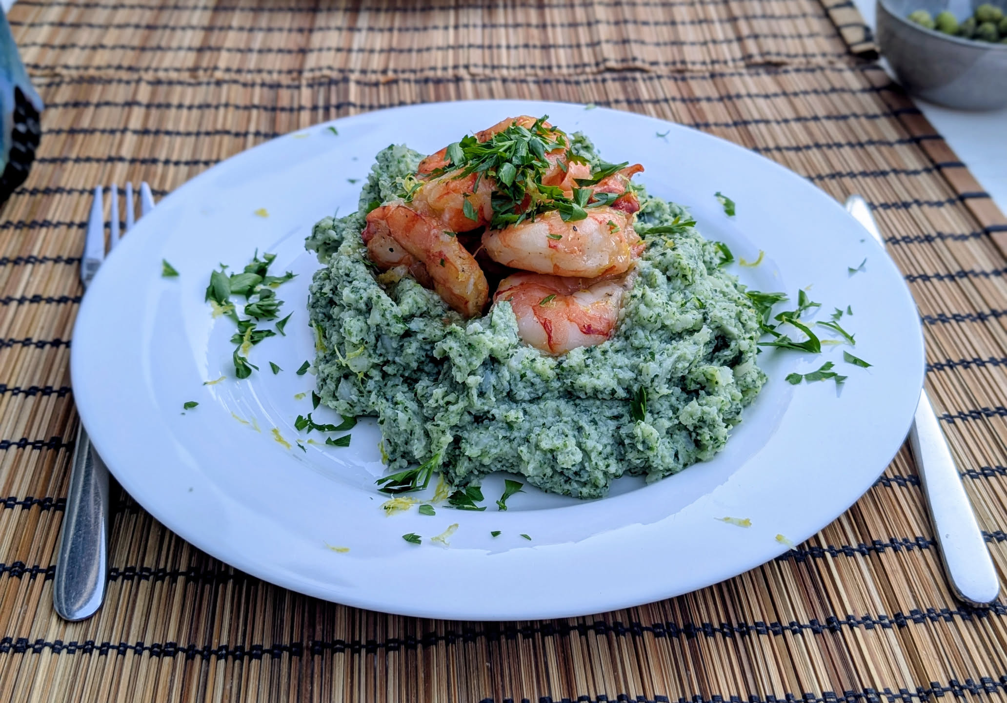 Crevettes sous vide au citron posées sur un lit de purée de choux-fleurs et d'épinards.