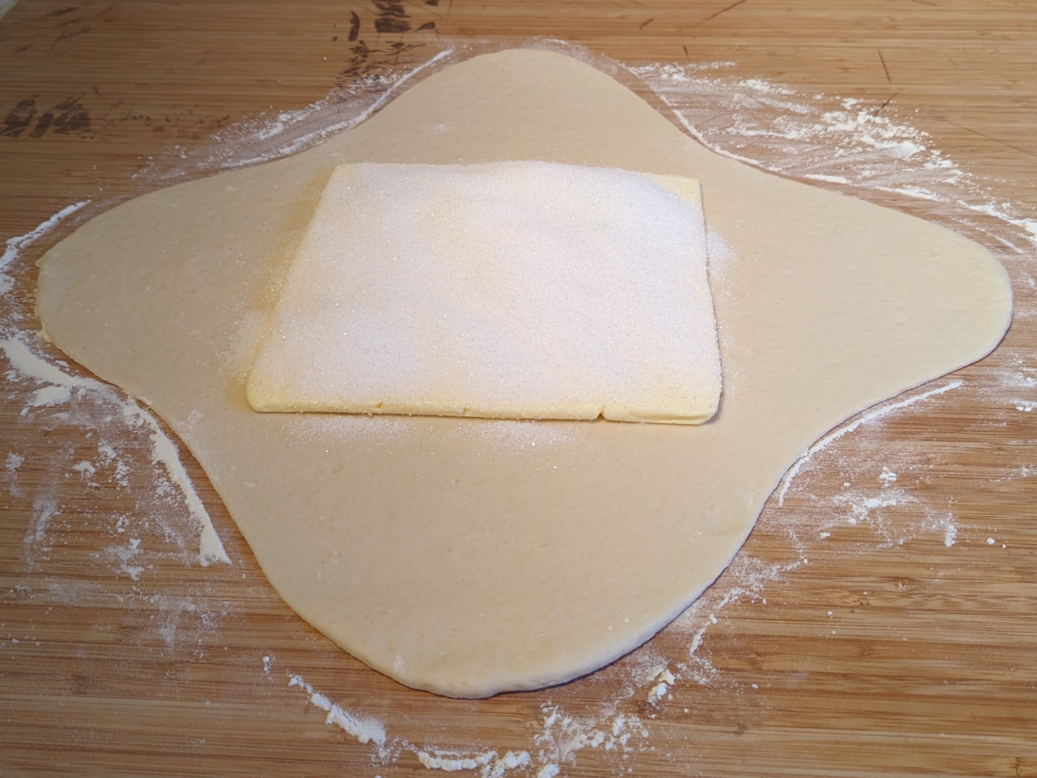 Pâte en croix avec une plaque de beurre au centre de la croix, recouverte de sucre